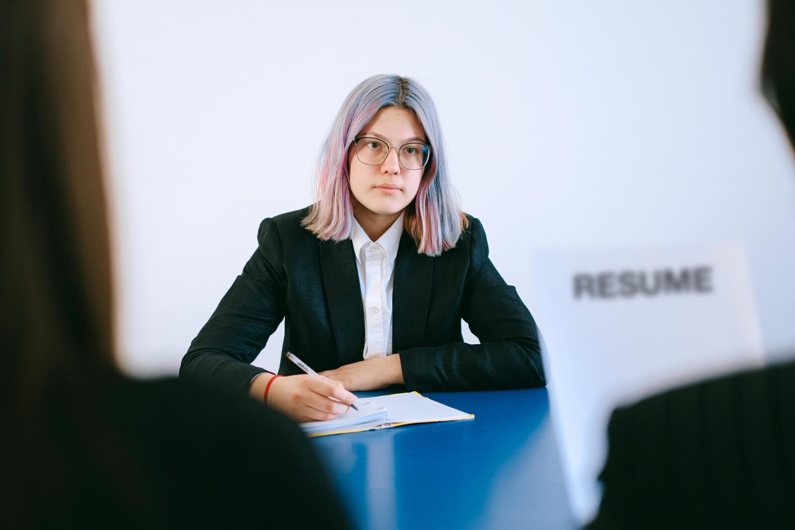 A young woman in a suit during a job interview, writing notes.