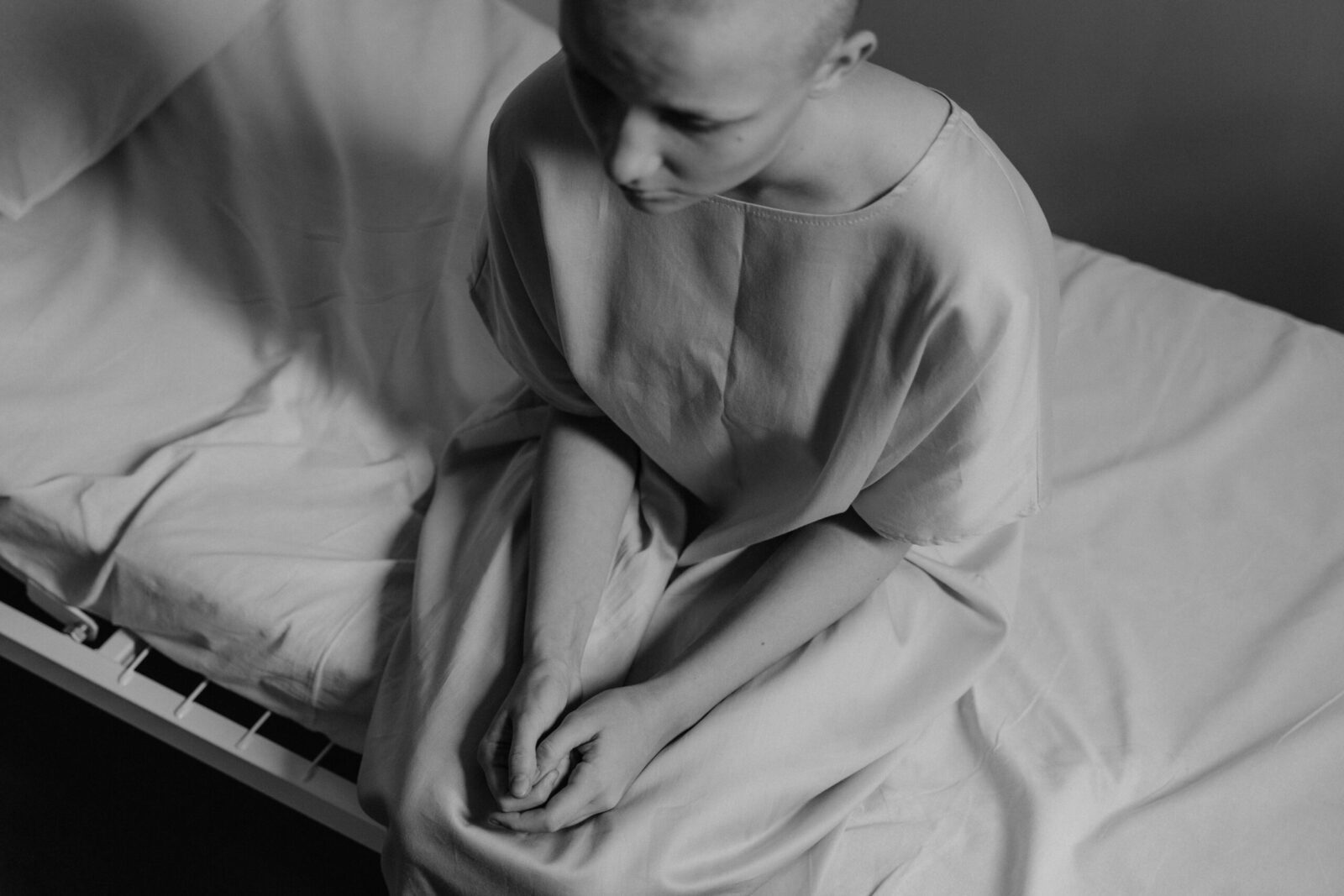 A poignant black and white photograph of a woman in a hospital setting, expressing vulnerability.