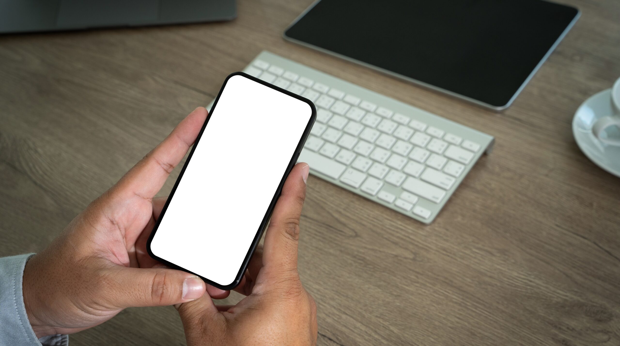 Photorealistic editorial still-life, 16:9. A smartphone on a desk displaying a colorful budgeting app with spending char